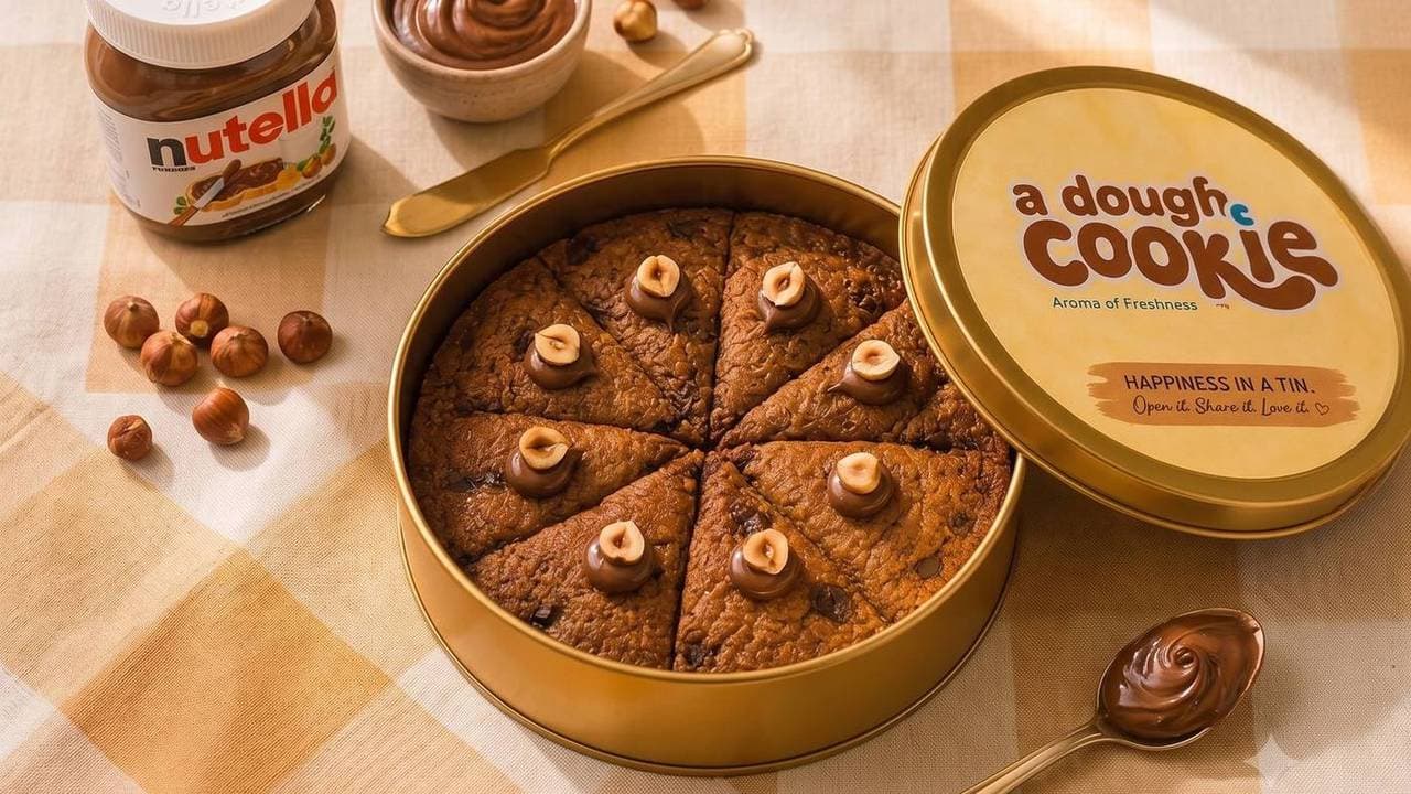 Nutella cookie tin with its lid off, next to a jar of Nutella and hazelnuts